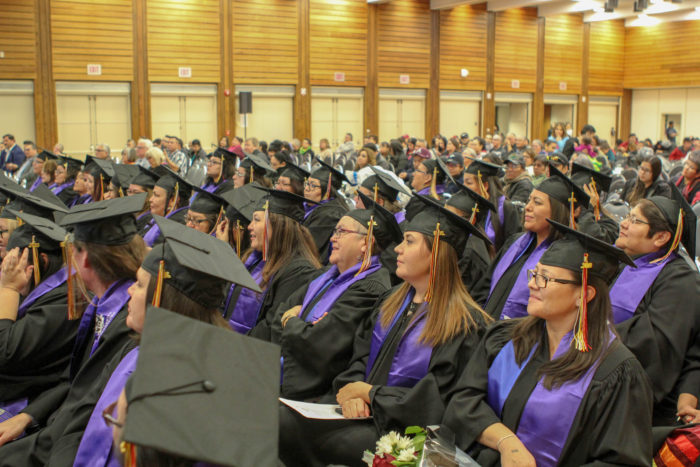 Adults wearing gowns and caps at a graduation ceremony